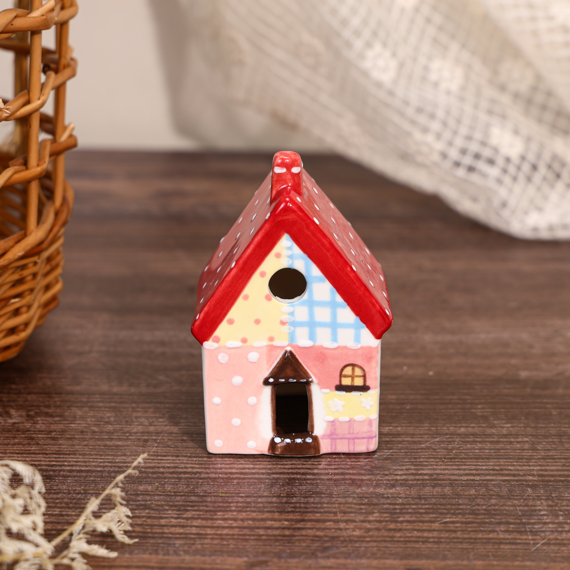 Hand-painted red roof ceramic house ornament with pink walls and blue patchwork details
