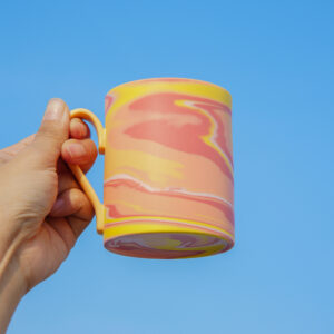 All Things Flourish marbled ceramic mug with yellow handle and pink yellow white tones