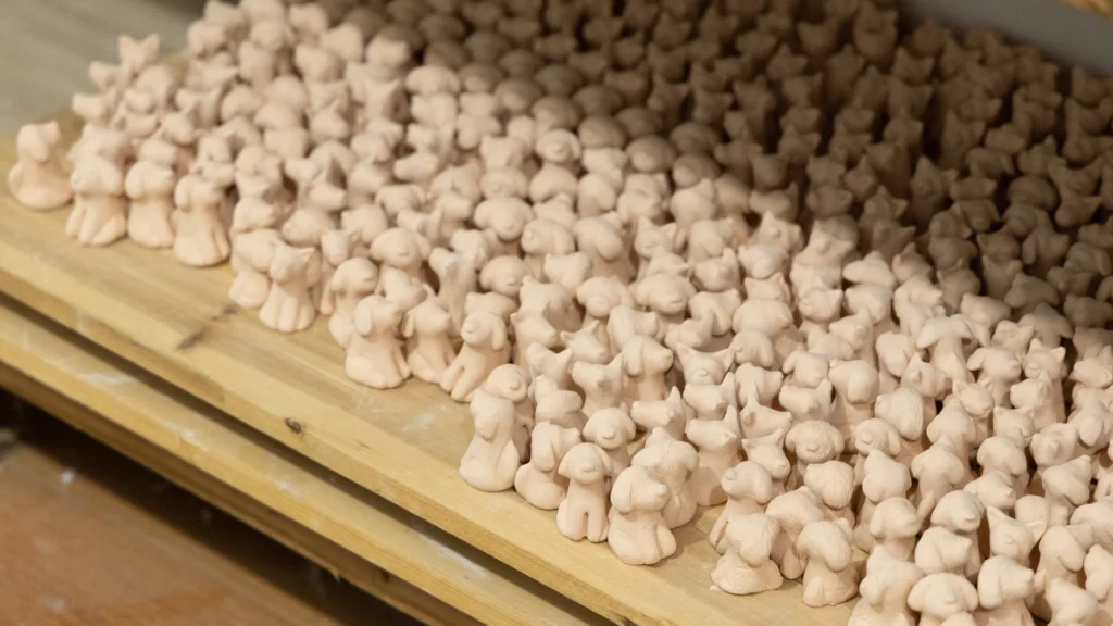Unfired ceramic pieces drying on workshop shelves